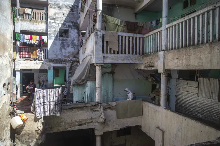 A person in protective personal equipment disinfects a crowded housing complex in Morocco.