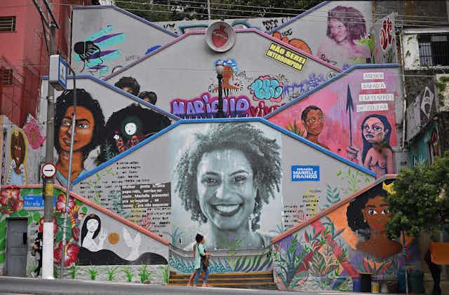 Mural featuring Black women, with a few people walking in front of it