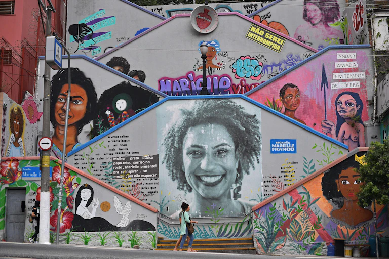 Mural featuring Black women, with a few people walking in front of it