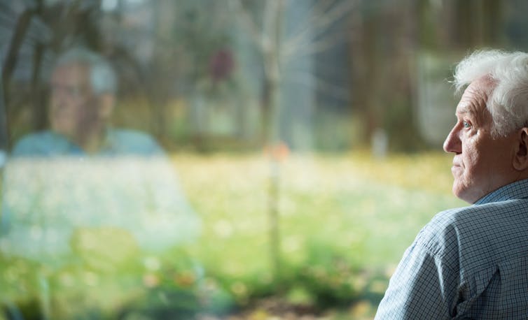 Lonely older man looking out of window