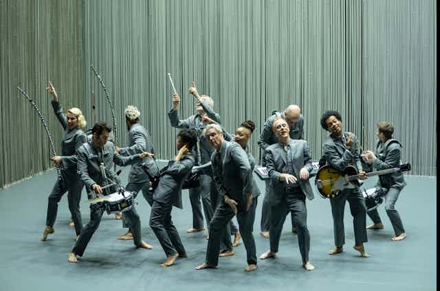 David Byrne with musicians dance on stage.