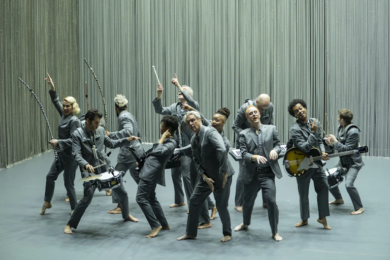 David Byrne with musicians dance on stage.
