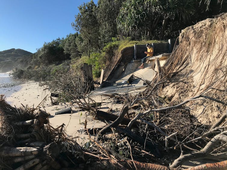 Man sitting near eroded beach