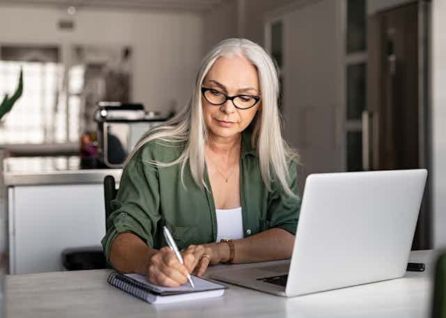 A woman studying using a laptop and taking notes