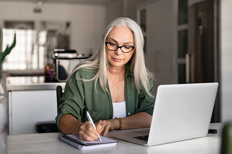 A woman studying using a laptop and taking notes