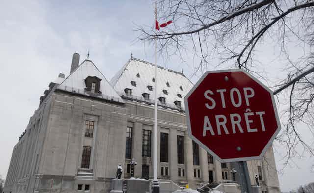 The snow-covered Supreme Court of Canada is seen with a stop sign in the foreground.