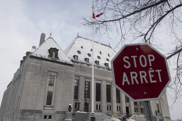 The snow-covered Supreme Court of Canada is seen with a stop sign in the foreground.