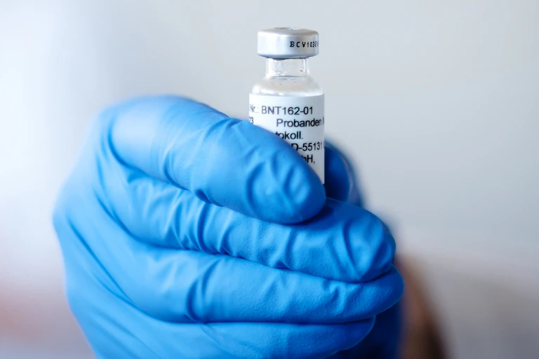 A hand holding a vial of COVID vaccine.