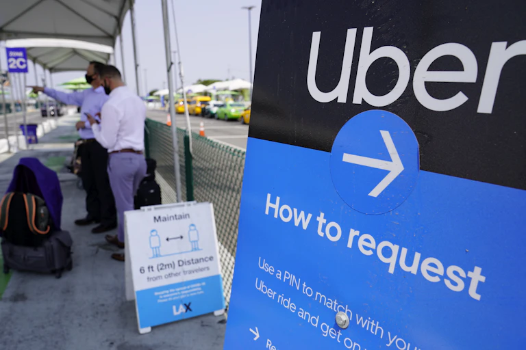 Men in masks stand near an Uber sign.