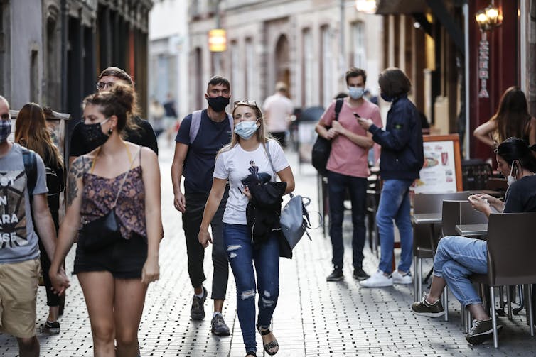 Des jeunes portant des masques dans une rue pavée.