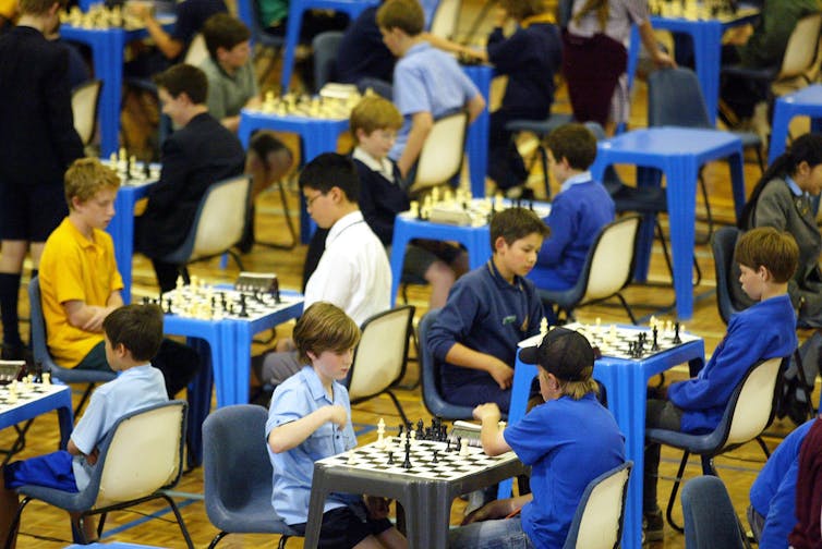 Children play chess in school uniform.