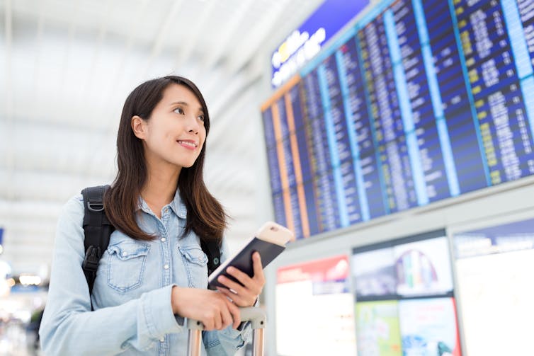 Young Chinese women looks up at airport departures board