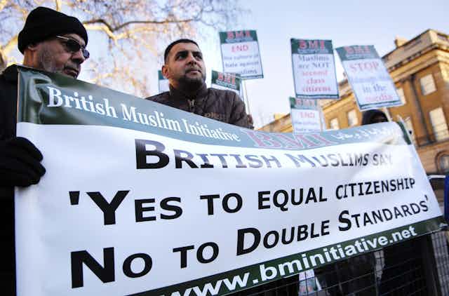 British Muslims holding banner reading 'British Muslims say yes to equal citizenship no to double standards'.