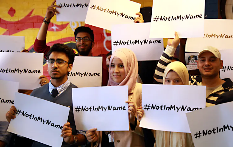 British Muslim school students holding signs saying '#notinmyname'.