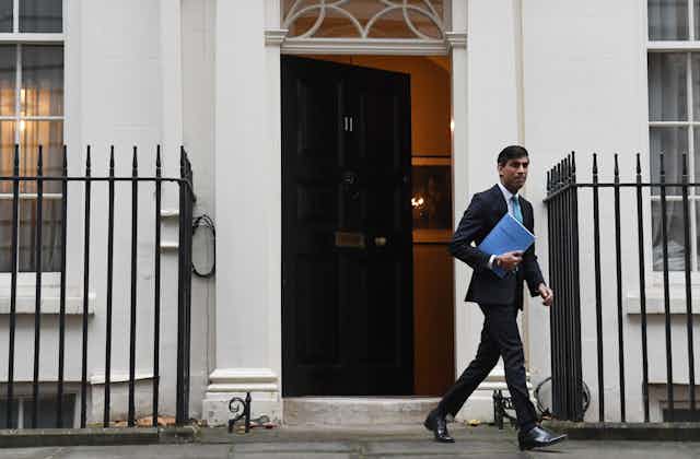 Rishi Sunak exits No.11 carrying a blue document labelled the spending review