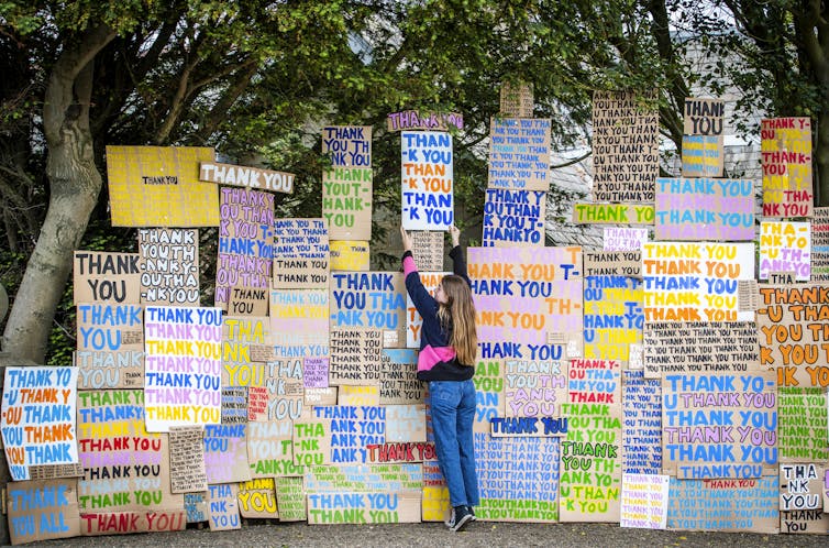 A girl in front of a wall of signs saying 