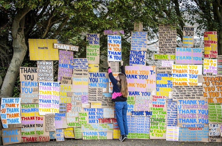 A girl in front of a wall of signs saying