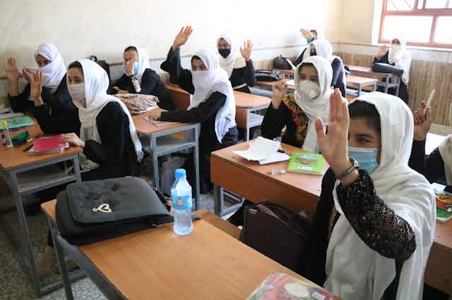 Afghan schoolgirls in a classroom wearing COVID masks.