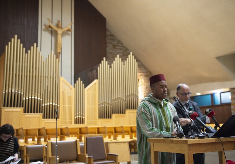 Two Muslim men stand in a church's pulpit.