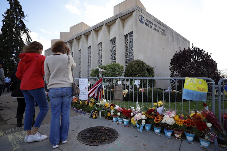 Poeple stand outside a makeshift commemoration in front of a synagogue