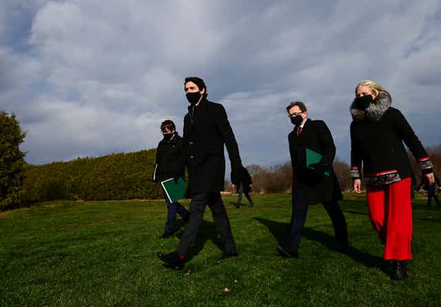 Prime Minister Justin Trudeau and three ministers walking across a field. 