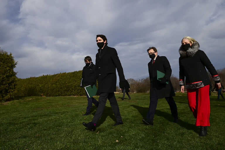 Prime Minister Justin Trudeau and three ministers walking across a field.