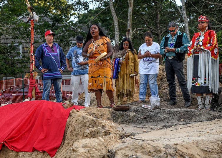 Shinnecock tribe members hold a prayer service on a site where human remains, likely belonging to the Shinnecock Nation, were unearthed.