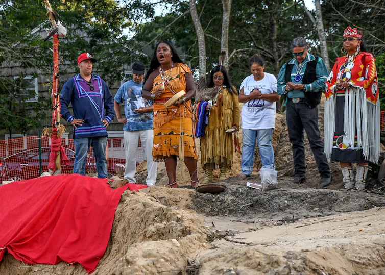 Shinnecock tribe members hold a prayer service on a site where human remains, likely belonging to the Shinnecock Nation, were unearthed.