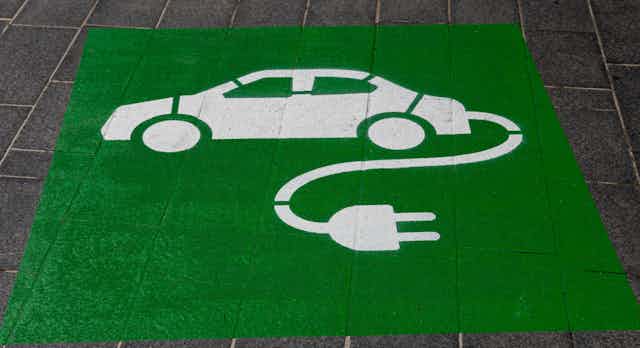 Stenciled sign on pavement of electric vehicle. 