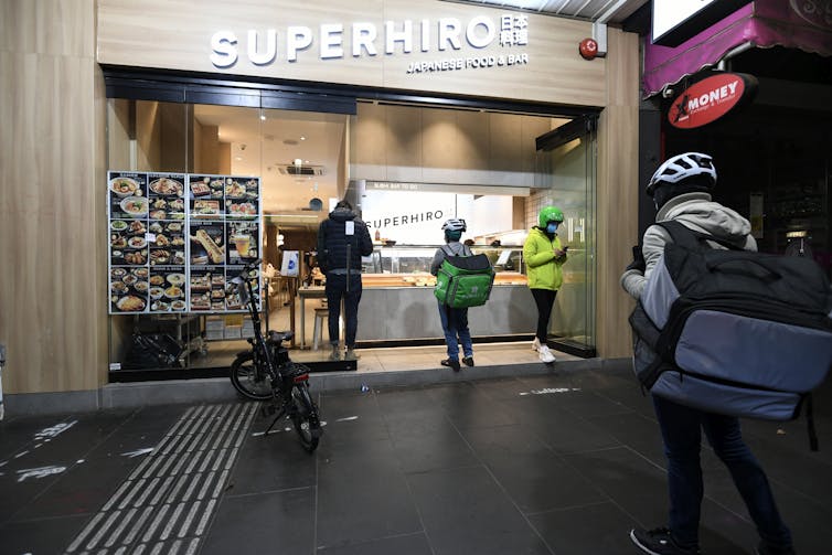 Food delivery riders wait to pick up orders