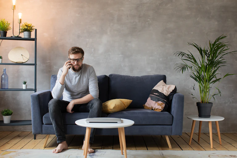 Man sits on the couch at home talking on the phone.