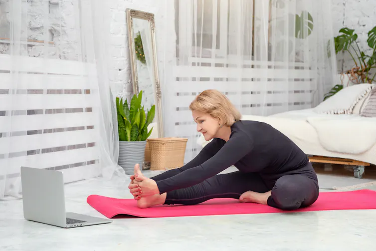 A woman on a red mat doing yoga in a white bedroom