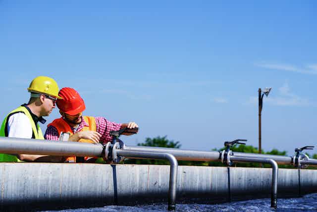 Two men testing water at a sewage treatment plant