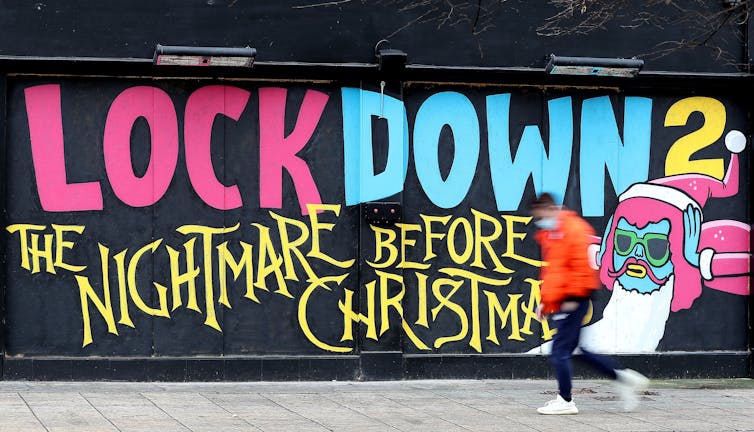 A man walks past a street mural saying 'Lockdown 2: the nightmare before Christmas'.