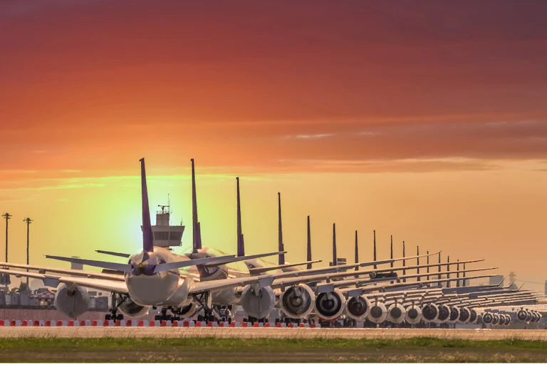 Aviones aparcados en línea durante la puesta de sol.
