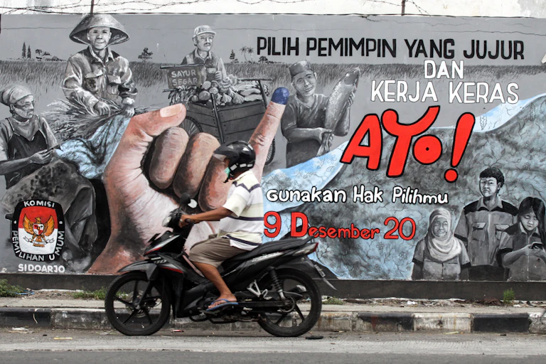 Pengendara melintas di depan mural bertema Pilkada serentak 2020.