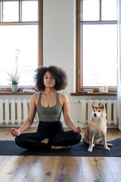 A woman and her dog on a yoga mat.