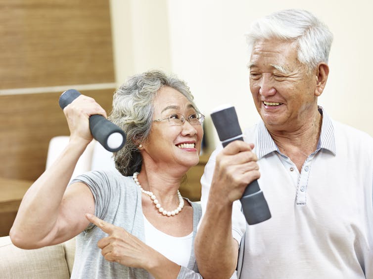 A man and a woman with gray hair with small dumbbells in their hands.