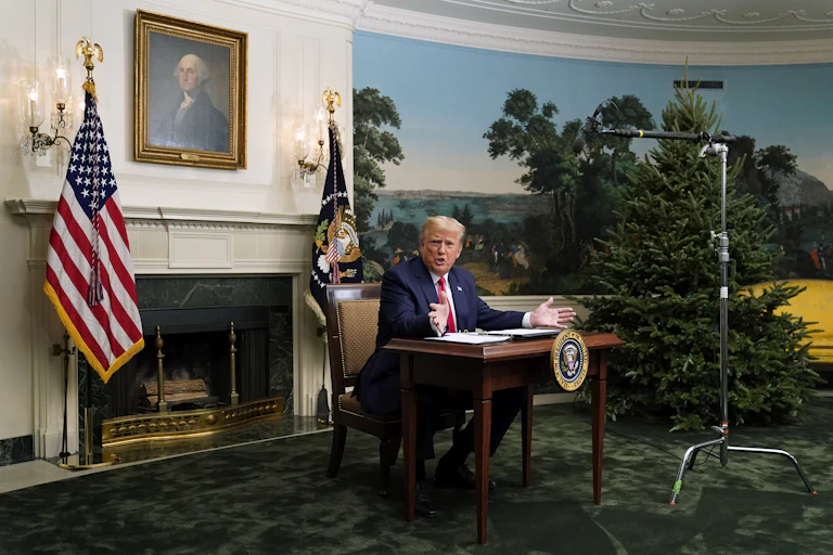 Donald Trump sits at a noticeably small desk at the White House