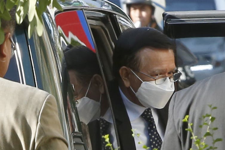 Kem Sokha steps out of car wearing facemask.