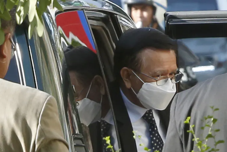 Kem Sokha steps out of car wearing facemask.