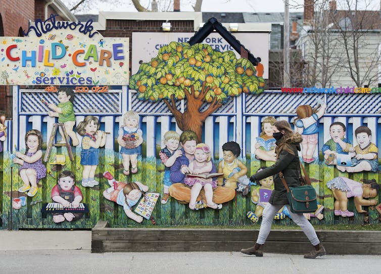A masked woman walks past a child care centre.