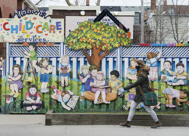 A masked woman walks past a child care centre.