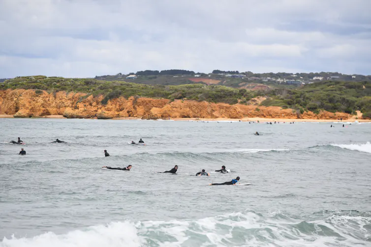 Surfers in Torquay on a cloudy day.