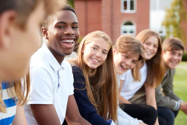 Group of 14 year old children sitting on school grounds.