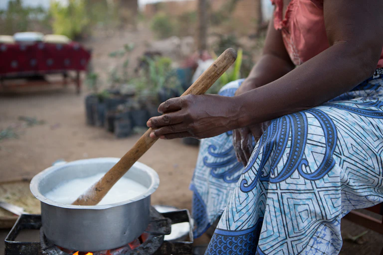 Woman cooking and stirring the pot with a wooden spoon.
