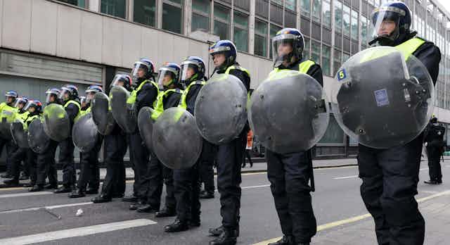 Riot police lined up with shields and helmets.