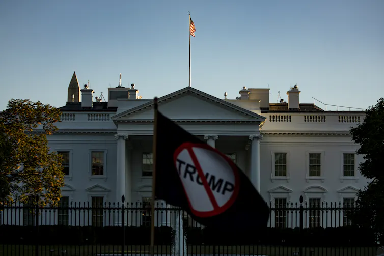 A protester holds up a 'Stop Trump' sign in front of the White House, October 2020.
