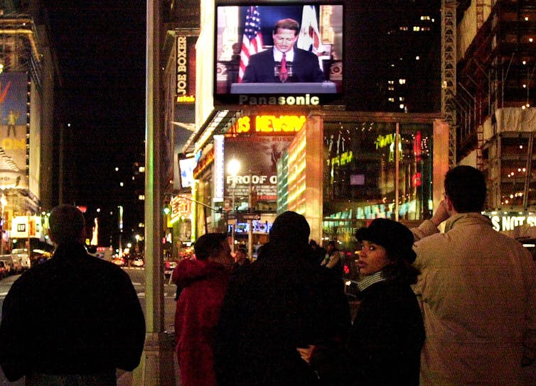 People in Times Square watch Vice President Al Gore concede the race for president to George W. Bush December 13, 2000 on a giant video screen in New York City.