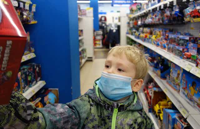 A boy reaches for a toy in a store.